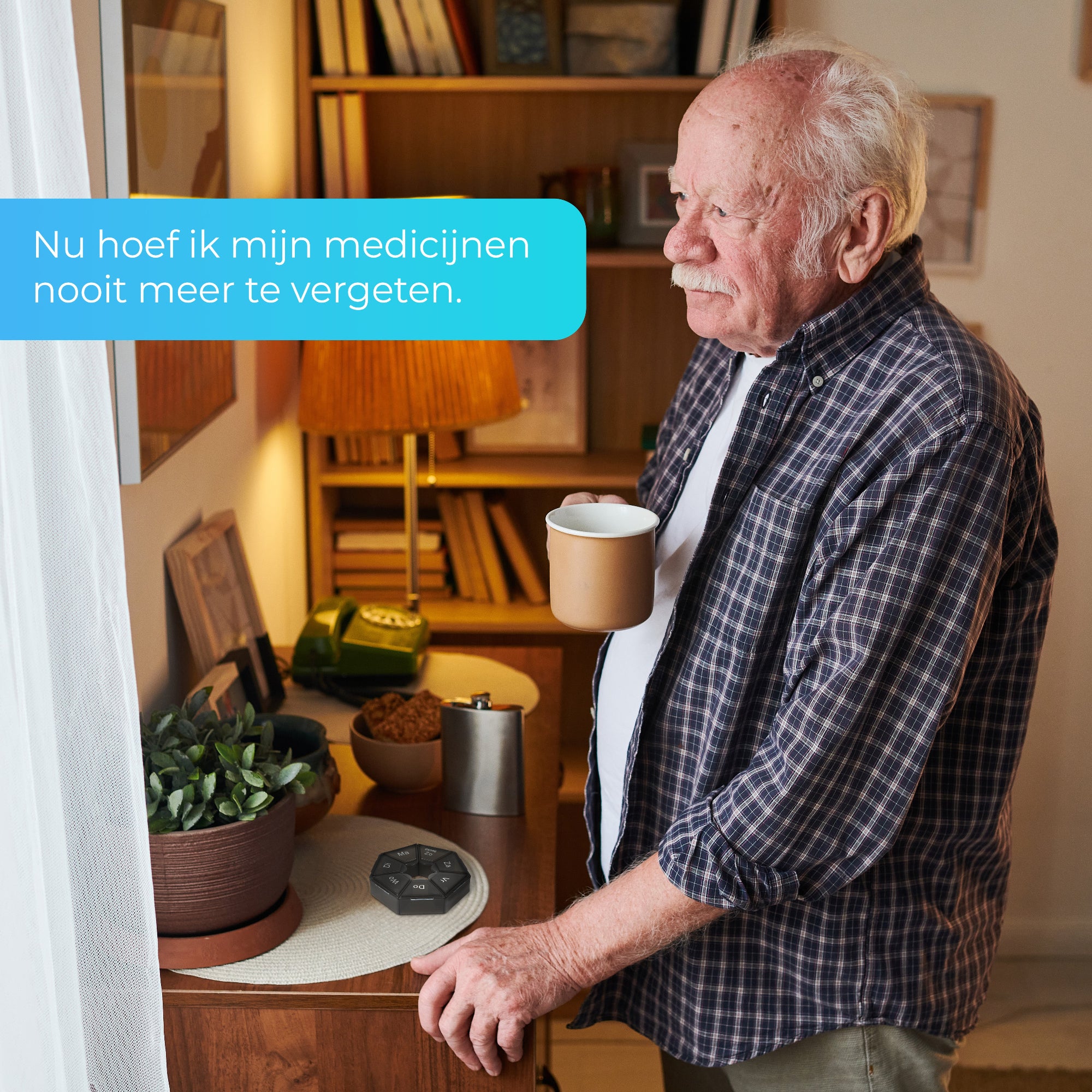 Oudere man kijkt uit het raam met een kopje koffie in de hand, terwijl een ronde GEASY pillendoos zichtbaar op tafel ligt. "Nu hoef ik mijn medicijnen nooit meer te vergeten." Geschikt voor medicijnherinnering bij ouderen.